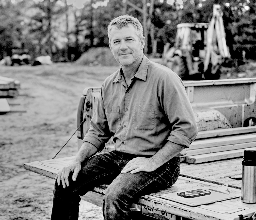 A business owner sitting on the tailgate of a work truck at a job site